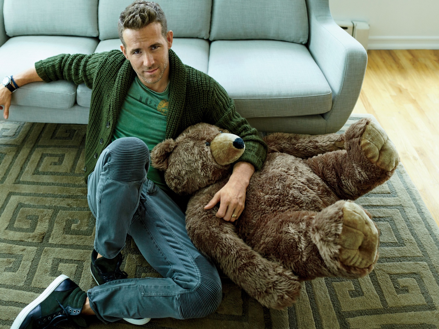 Актер Райан Рейнольдс с большим плюшевым медведем сидит на полу