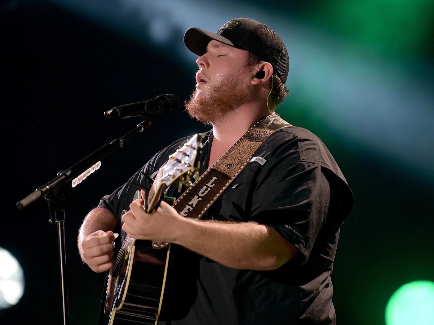 Кантри исполнитель Люк Комбс с гитарой поет на сцене