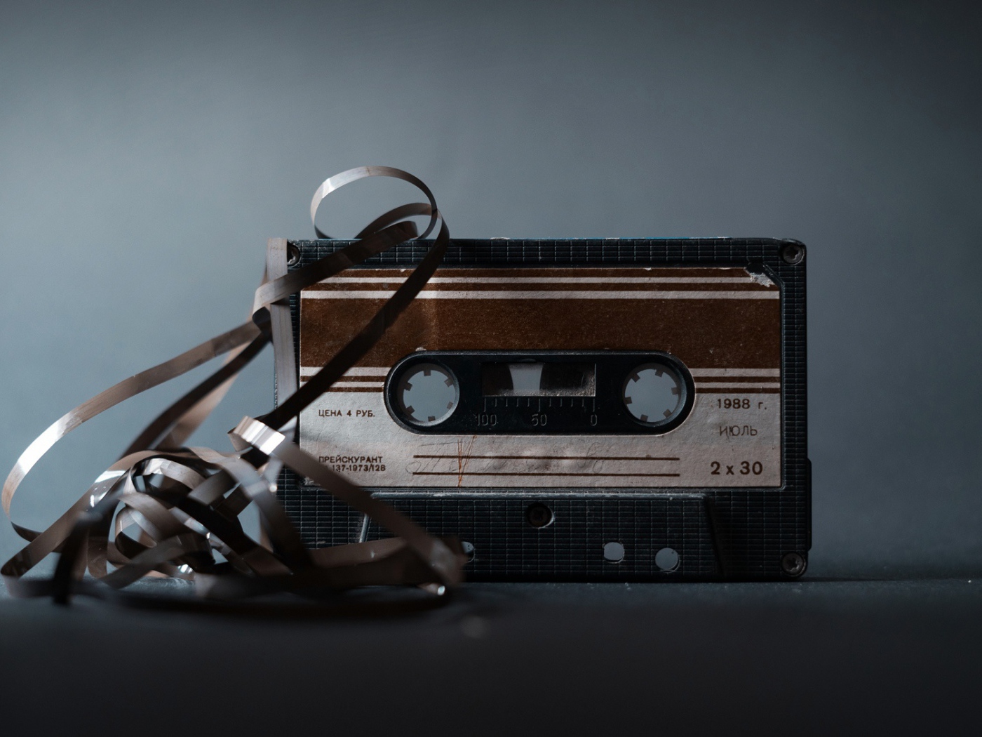 Старая кассета с вытянутой пленкой на сером фоне 