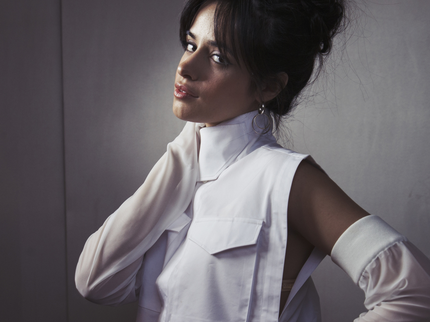 Молодая певица Камила Кабельо в белом костюме у стены