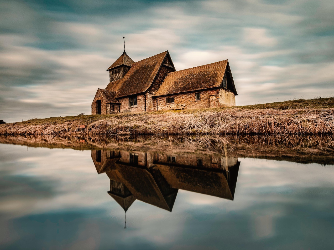 Старый дом на берегу реки отражается в воде