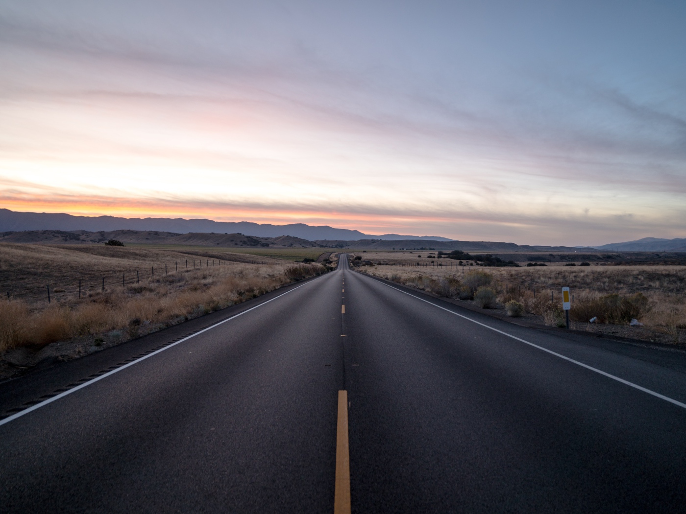 Асфальтная дорога уходит вдаль на фоне неба