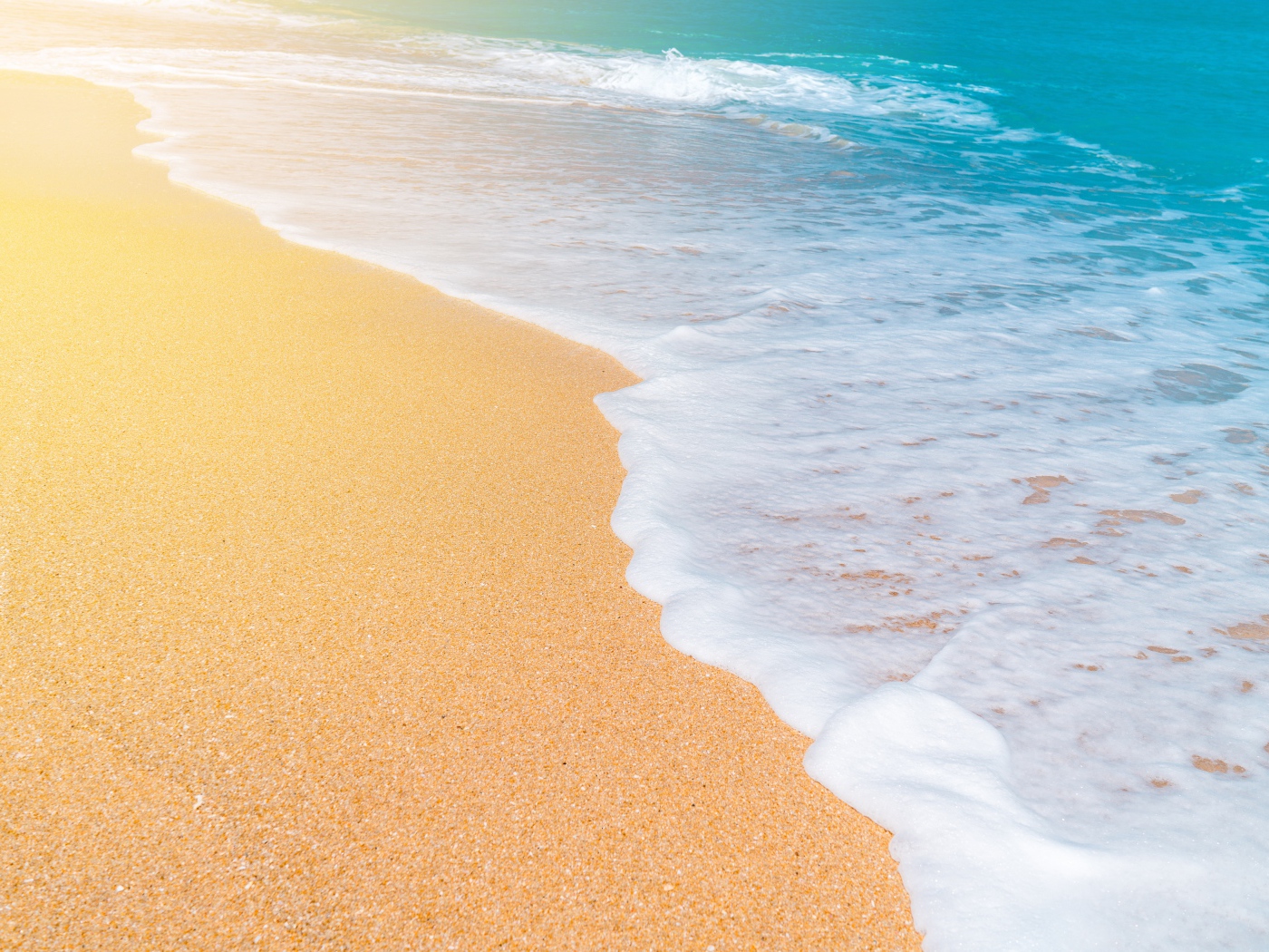 Белые волны океана омывают желтый горячий песок на пляже