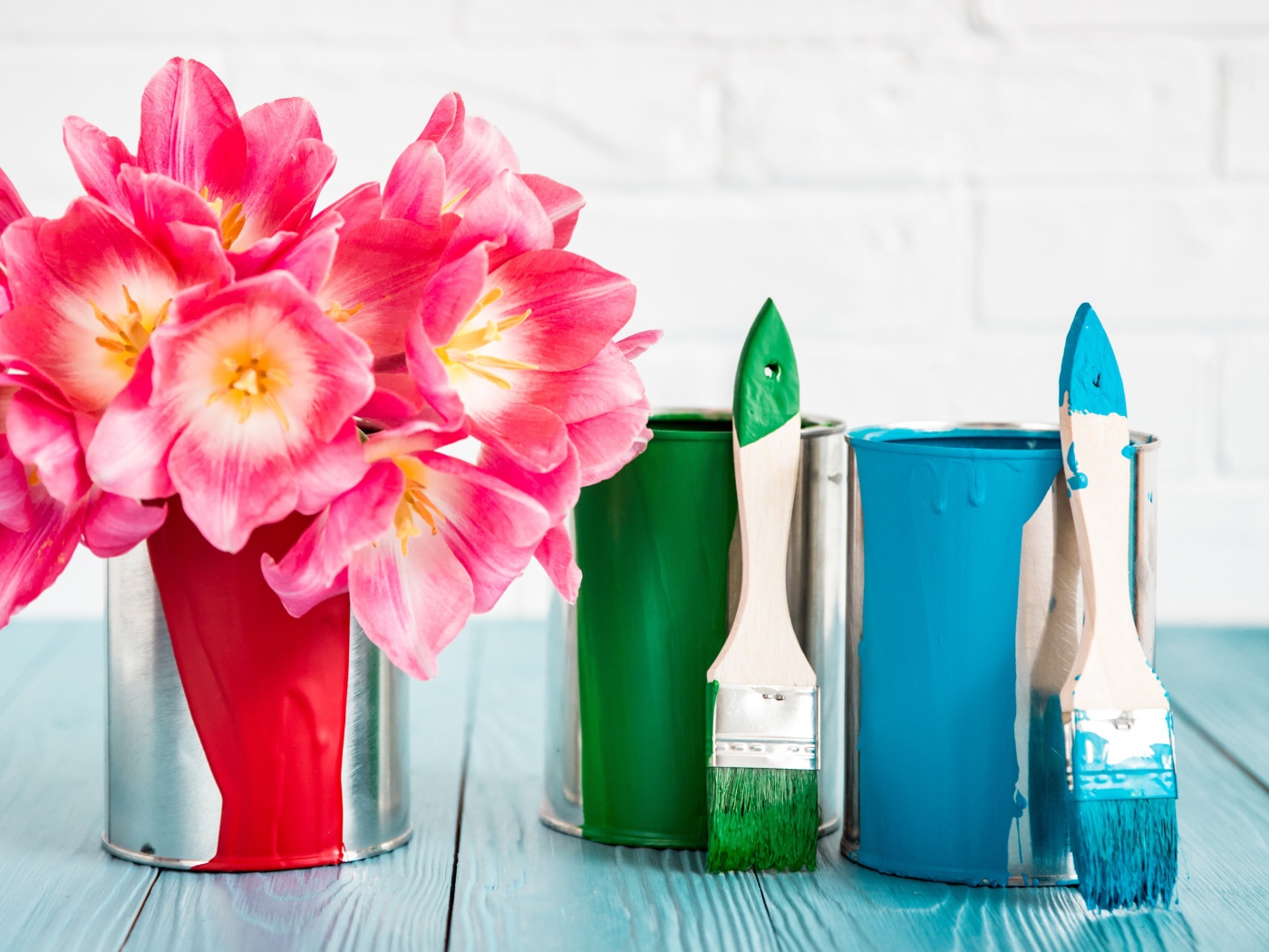 Букет розовых тюльпанов на столе с банками краски и кисточками