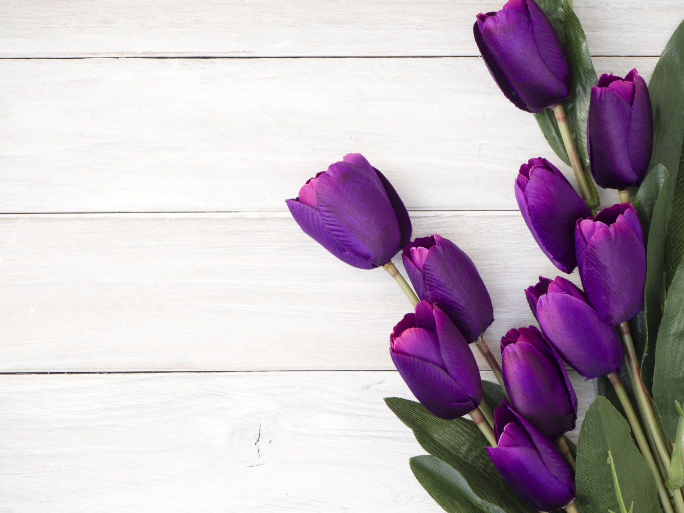 Букет искусственных фиолетовых тюльпанов на деревянном фоне
