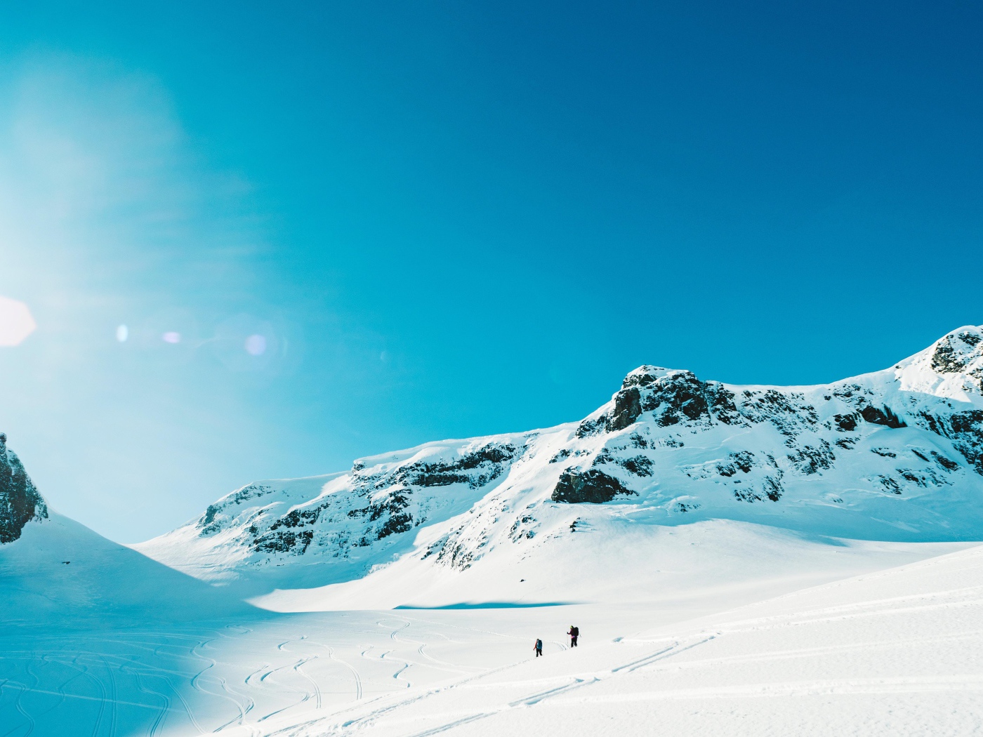 Красивые заснеженные горы под голубым небом в лучах солнца 