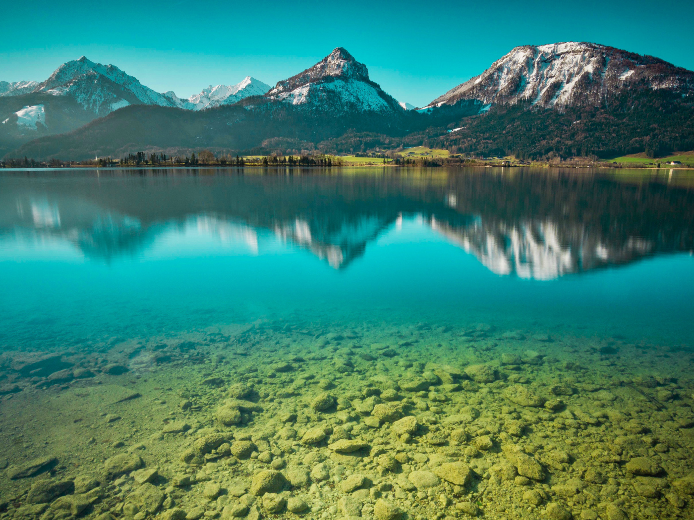 Заснеженные горы отражаются в чистой воде озера 