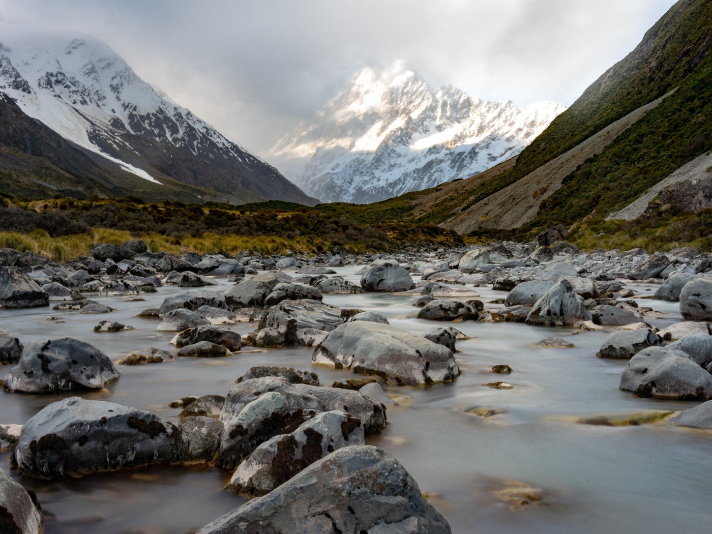 Камни в воде у заснеженных гор 