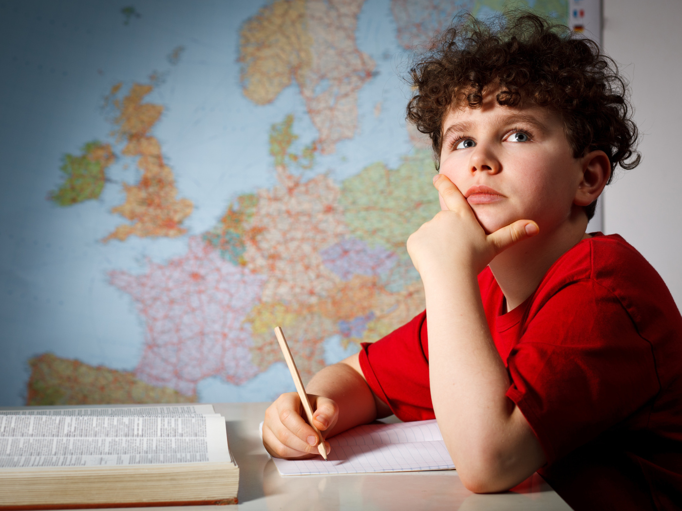 Мальчик ученик делает уроки за столом 