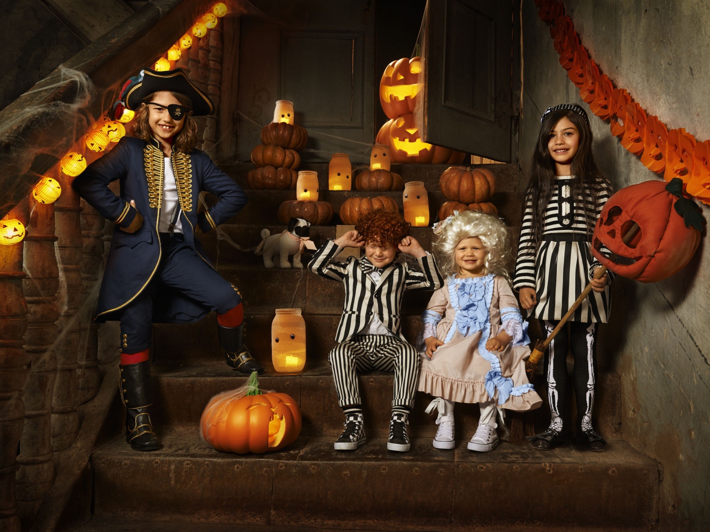 Дети в костюмах на Хэллоуин с тыквами на ступеньках