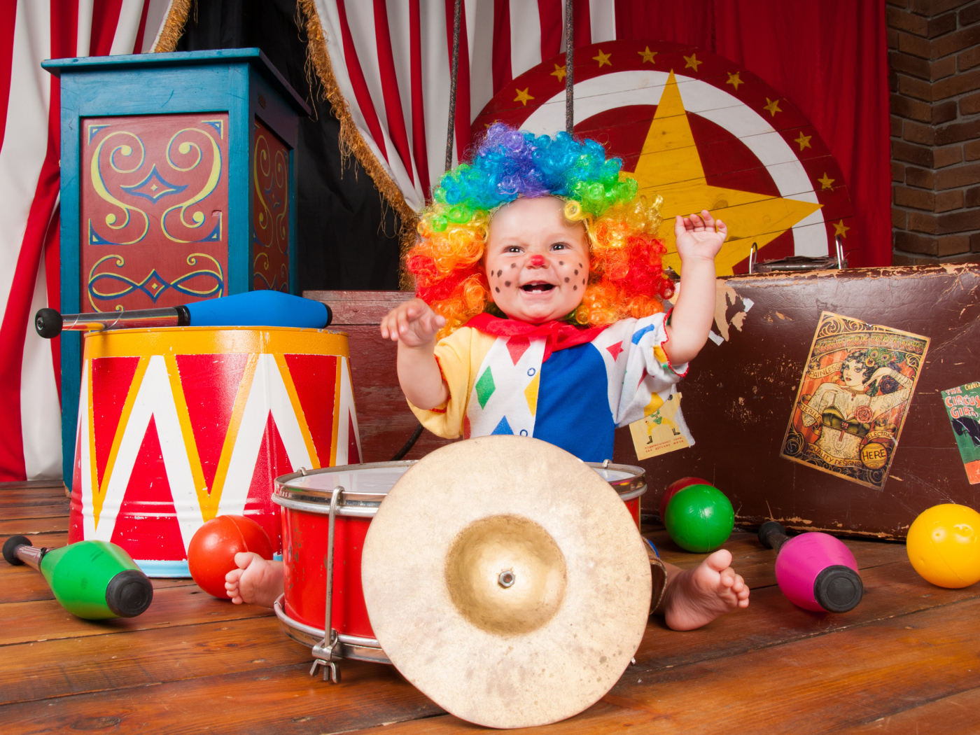 Маленький ребенок в костюме клоуна с музыкальными инструментами
