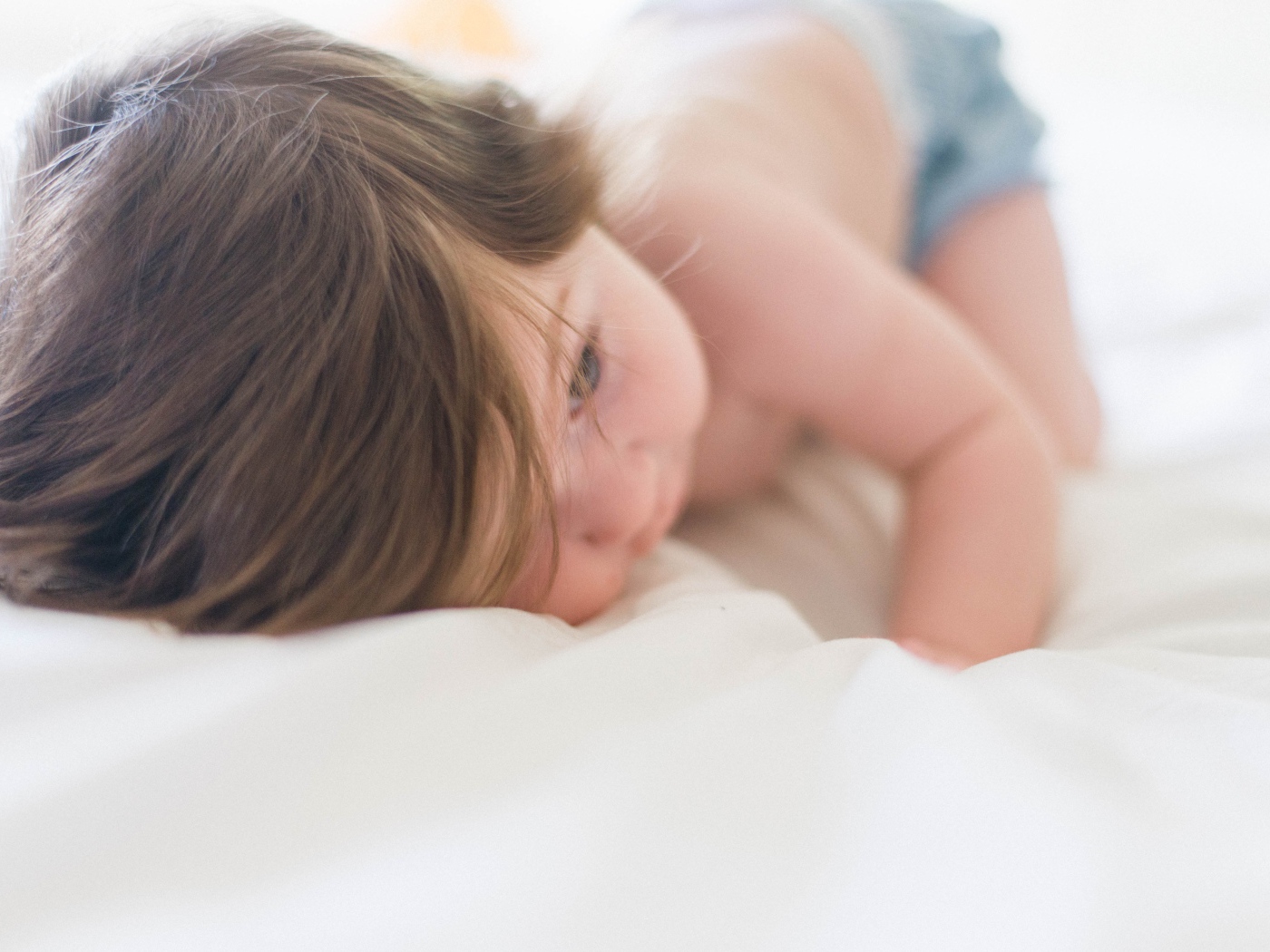 Маленький ребенок с русыми волосами лежит на кровати