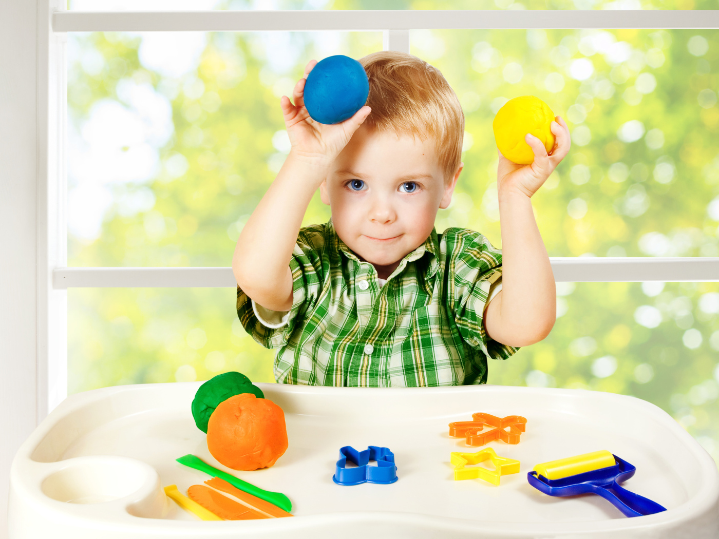 Маленький мальчик играет с игрушками у окна