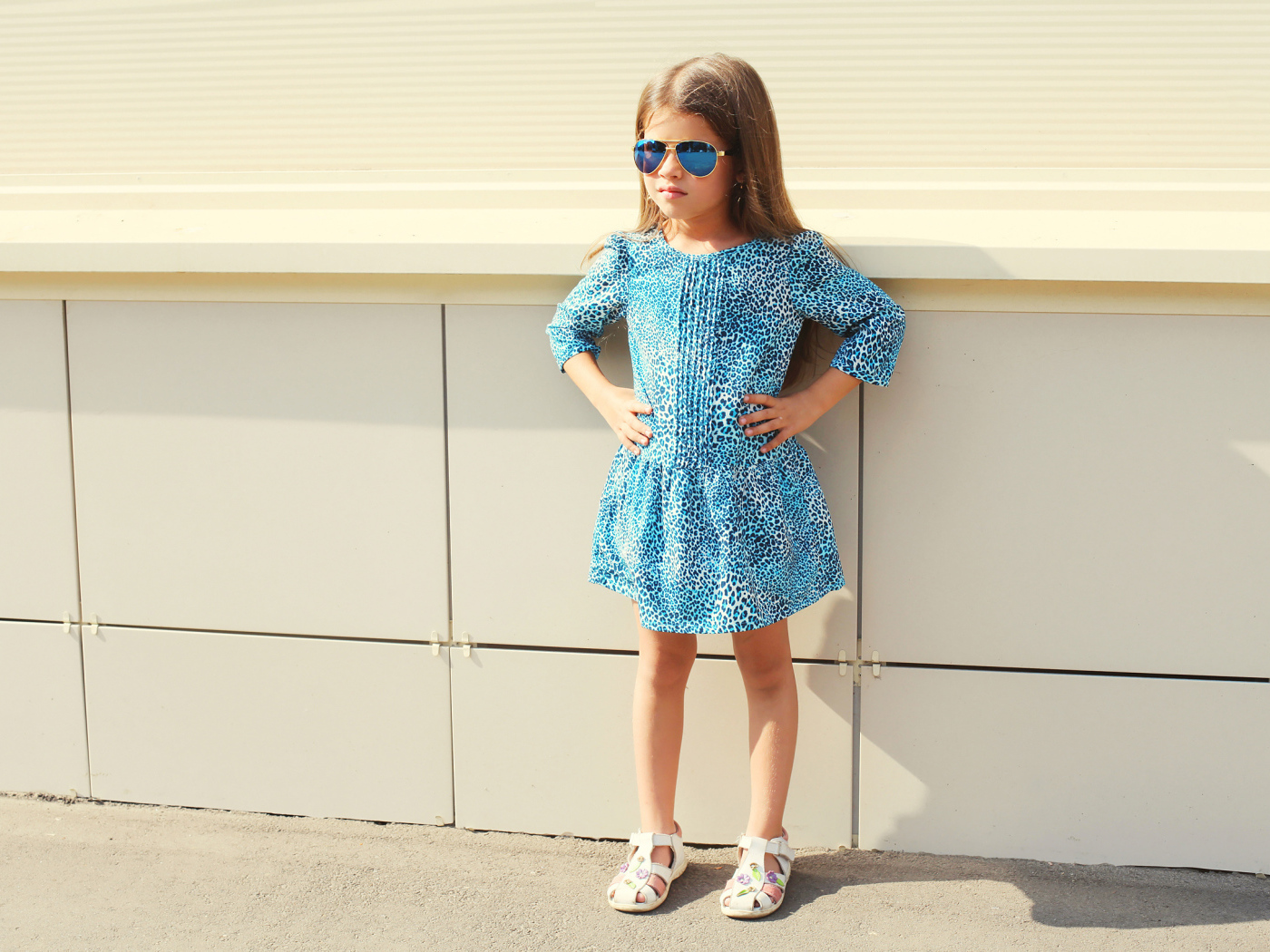 Маленькая девочка в красивом платье у стены