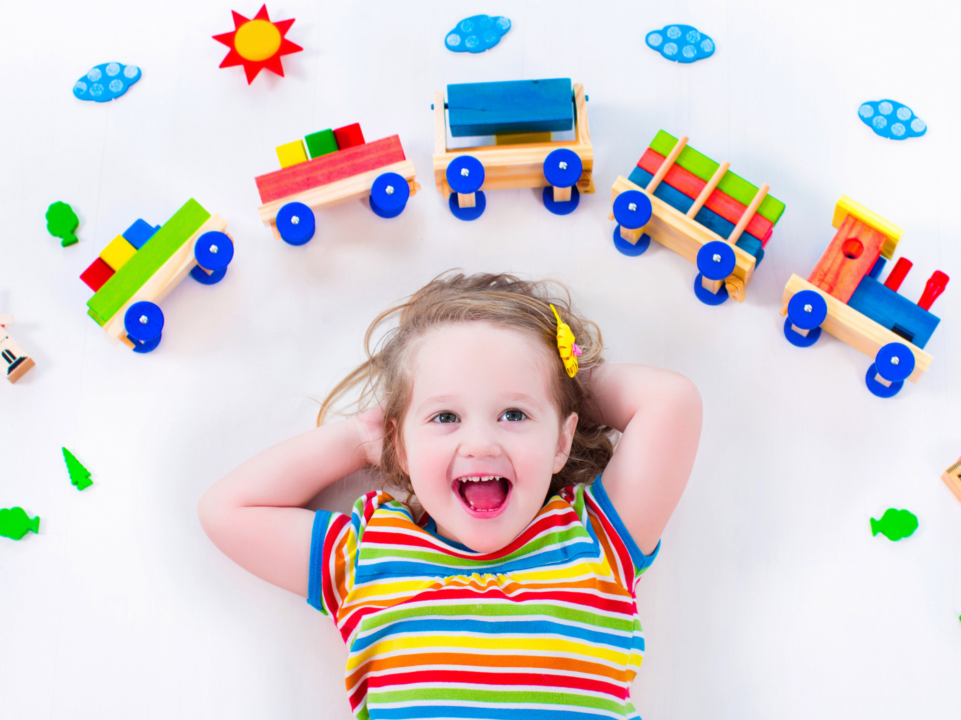 Маленькая девочка на сером фоне с игрушечным паровозом 