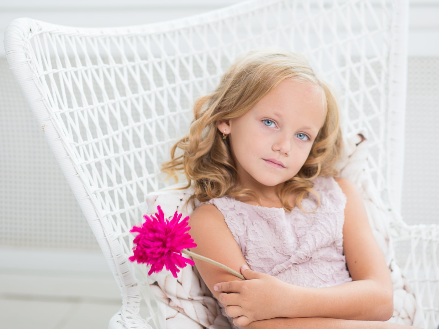 Маленькая девочка сидит в белом кресле с розовым цветком