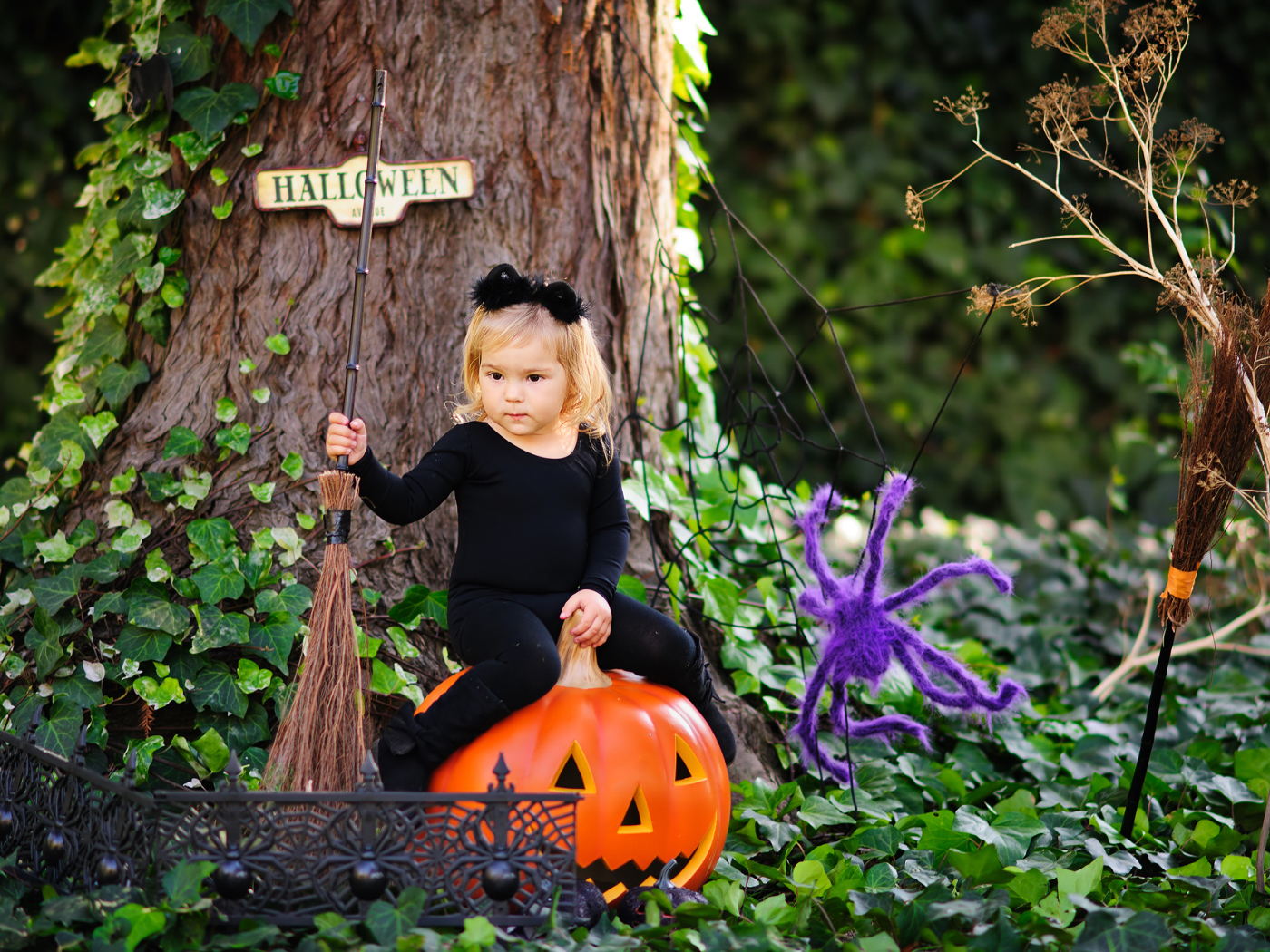 Маленькая девочка сидит на тыкве в лесу в костюме на Хэллоуин 