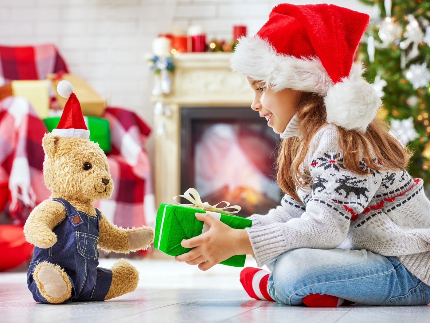 Маленькая девочка с медвежонком Тедди у елки с подарками на Новый год