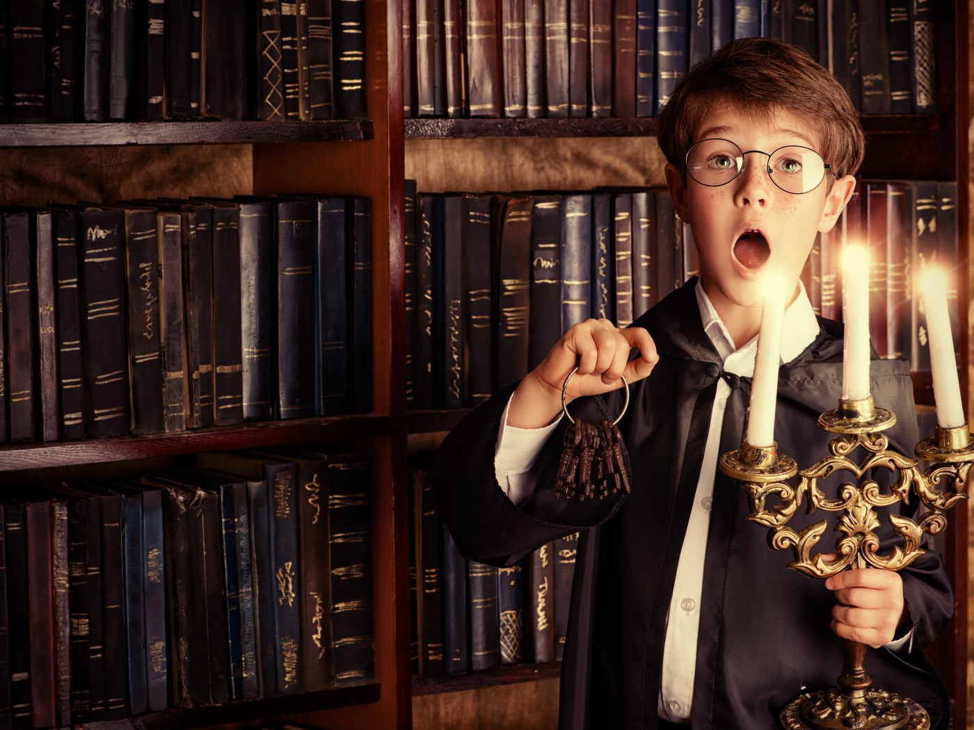 Удивленный мальчик с подсвечником со свечами в библиотеке
