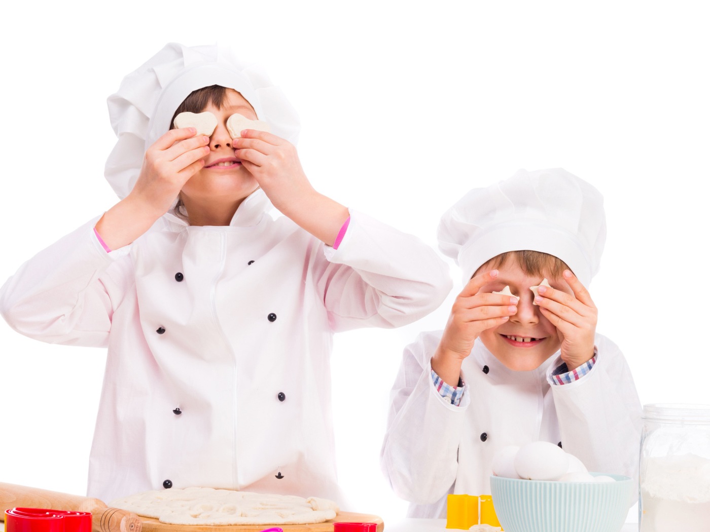 Два маленьких мальчика в костюмах повара на кухне делают печенье