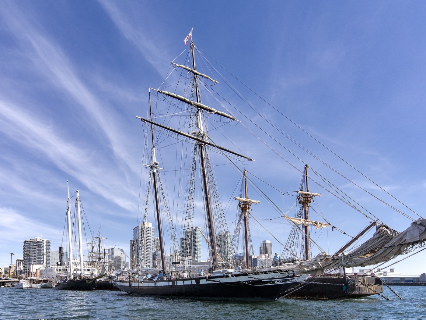 Большая парусная лодка на фоне голубого неба в порту у города