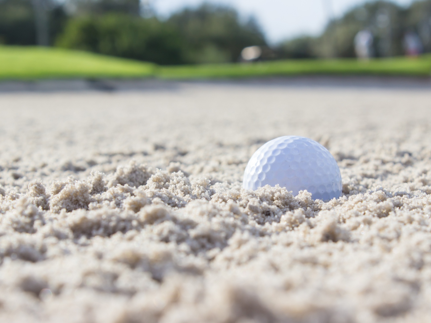 Белый мяч для гольфа лежит на песке