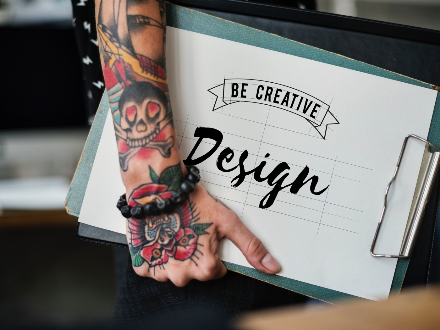 Мужчина с татуировкой на руке держит папку