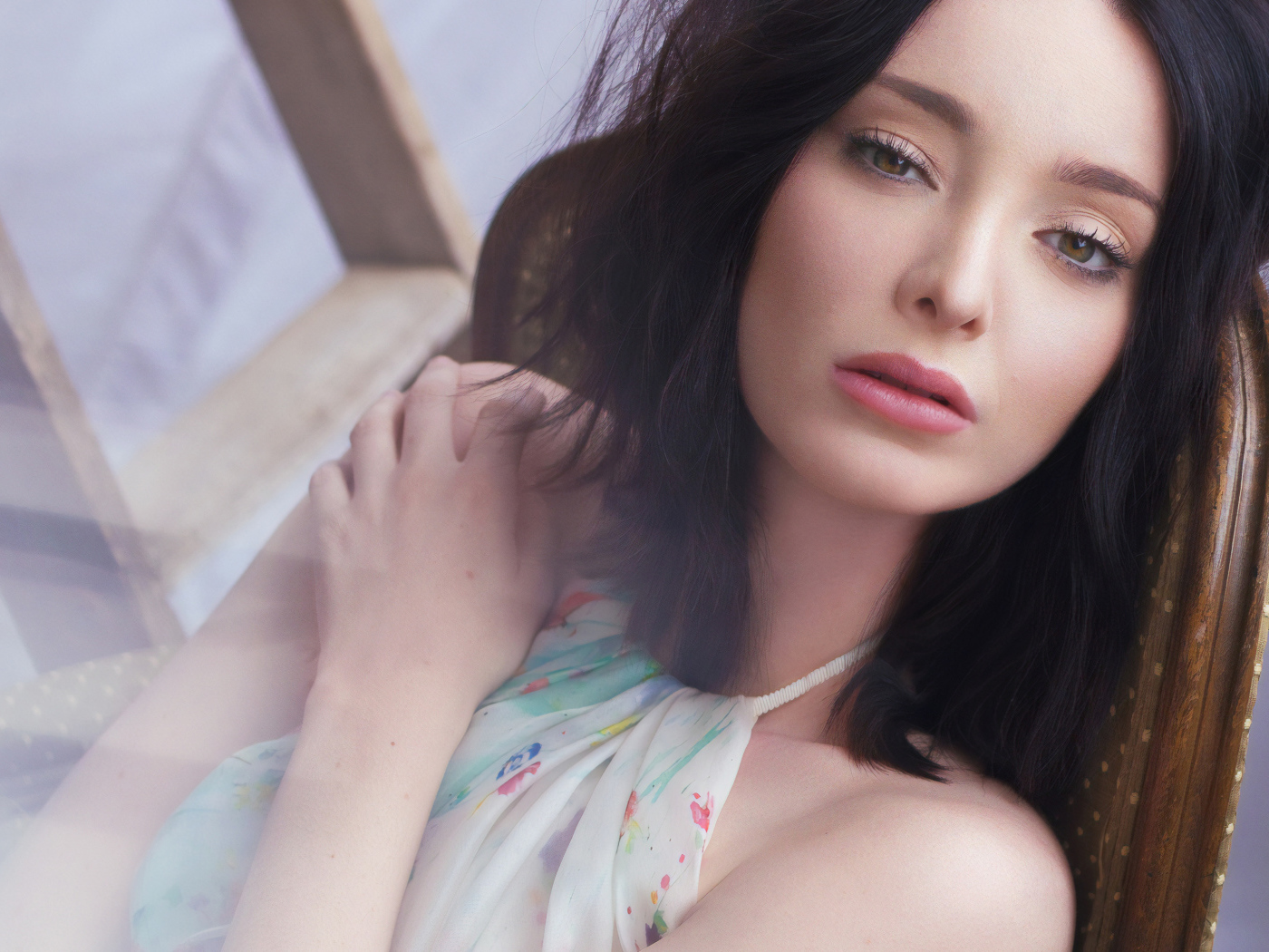 Красивая брюнетка, актриса Эмма Дюмон сидит на стуле 