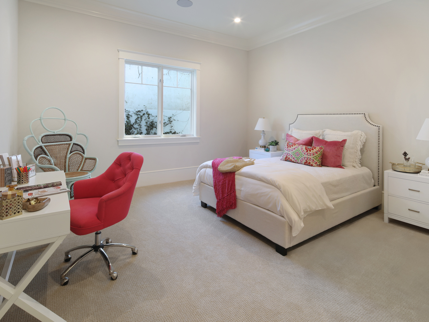 Спальня в светлых тонах с кроватью и столом с красным креслом