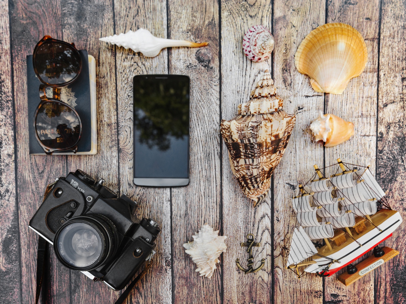 Camera, smartphone, shells, glasses and passport on the table