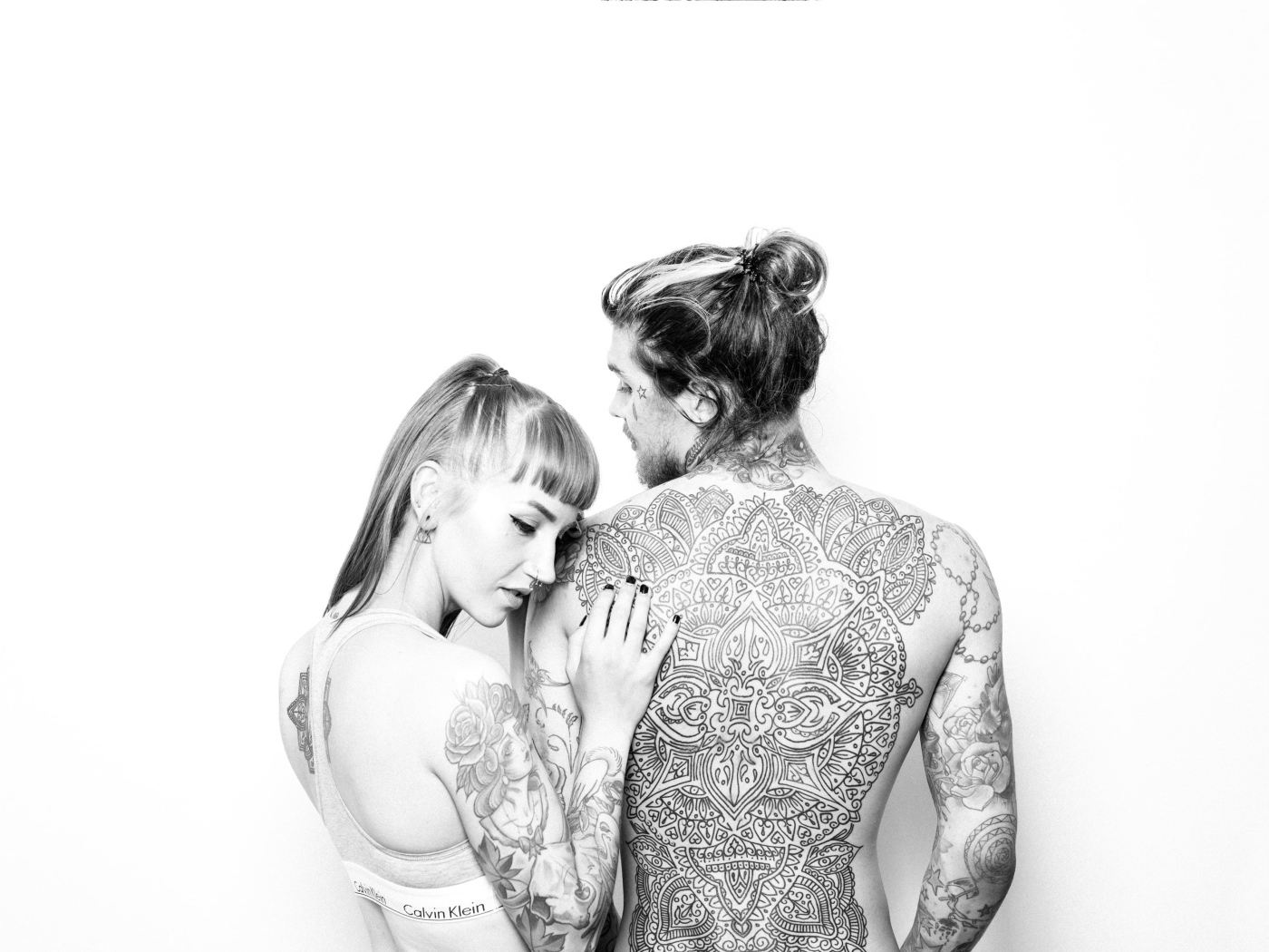 Мужчина и девушка с татуировками на теле на белом фоне