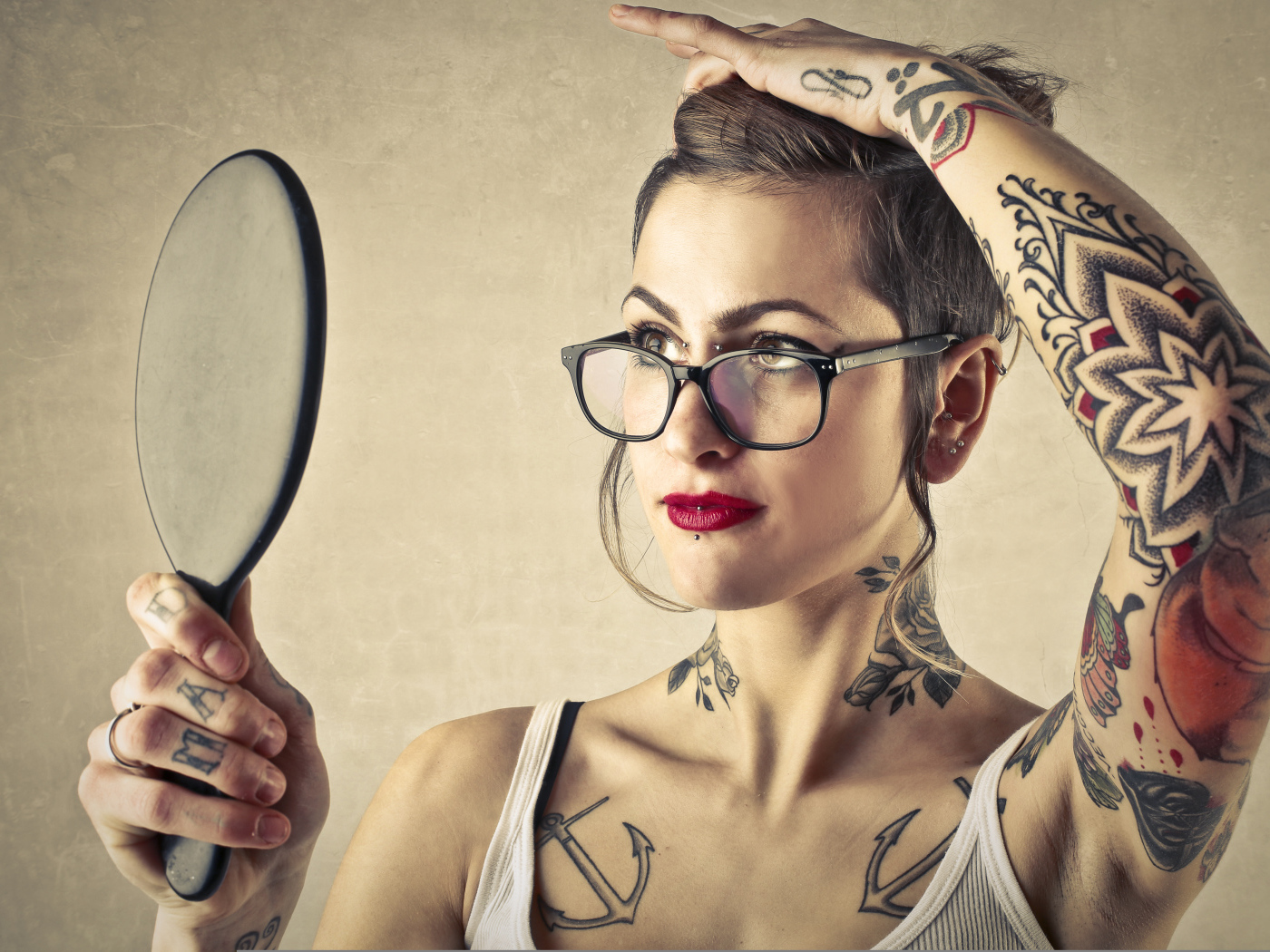 Девушка с татуировками на теле смотрит в зеркало