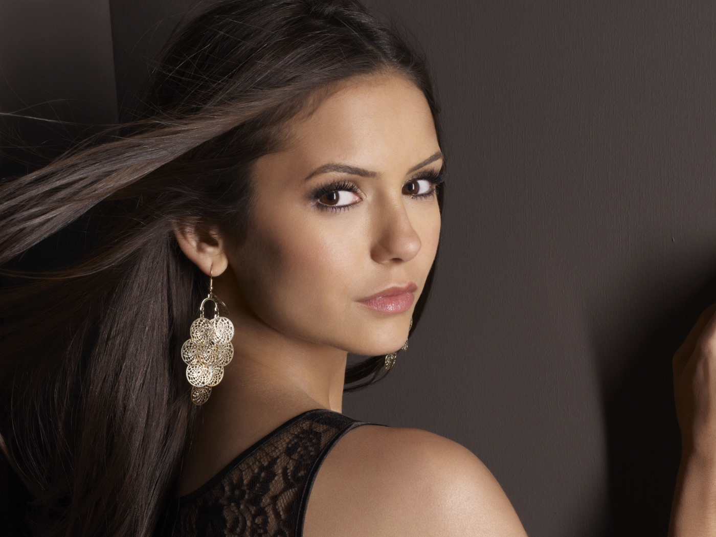 Ветер развивает волосы актрисы Нина Добрев на фоне стены