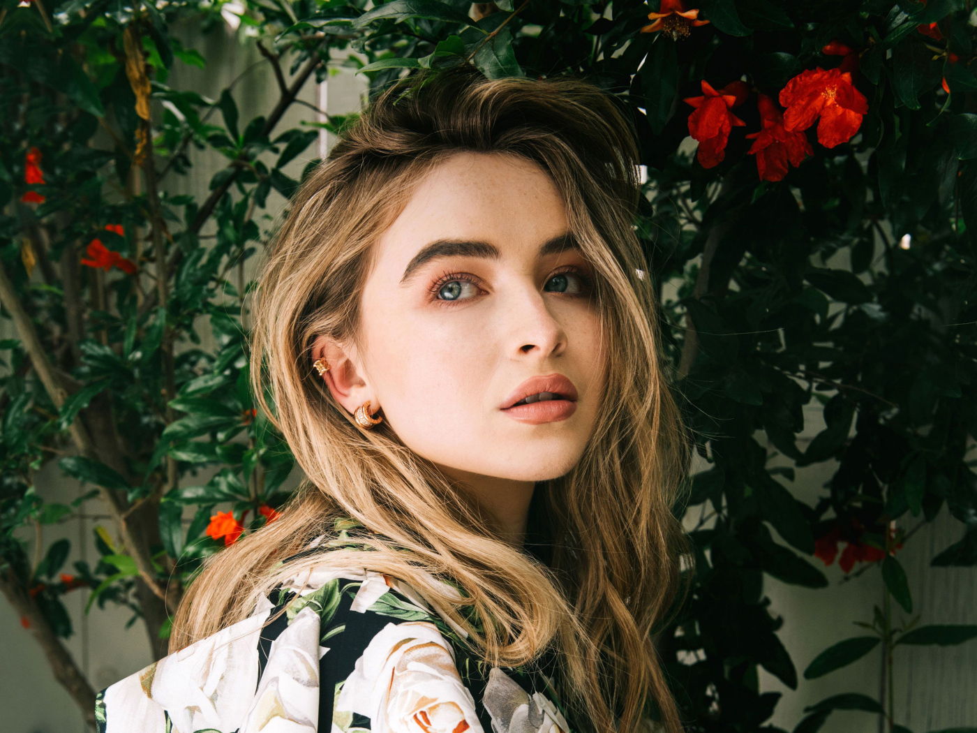 Молодая красивая актриса Сабрина Карпентер у красных цветов