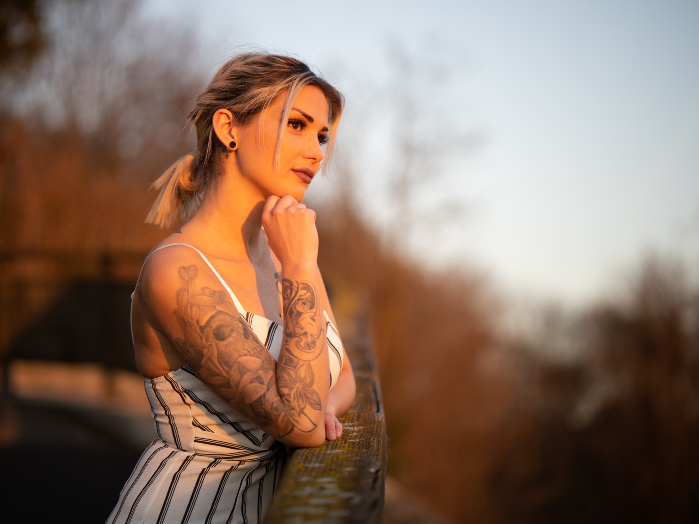 Молодая девушка с татуировкой на руке в лучах солнца