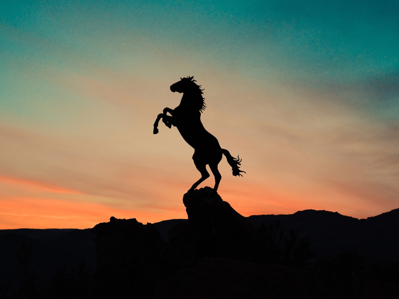 Силуэт коня на вершине горы на закате 