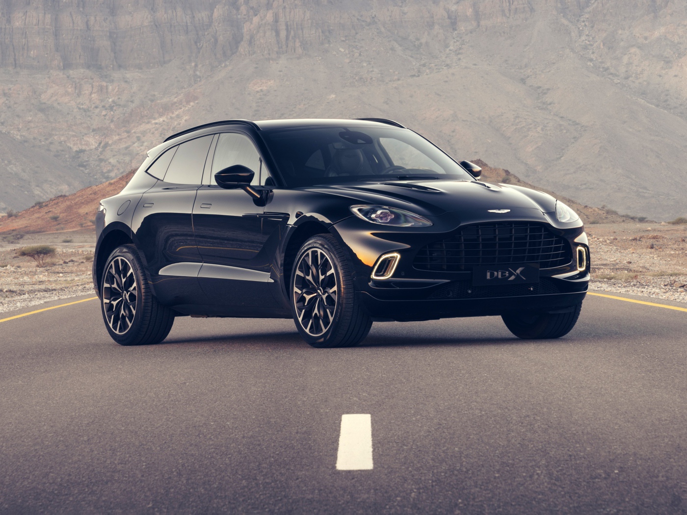 Черный автомобиль aston Martin DBX 2020 года на трассе в горах