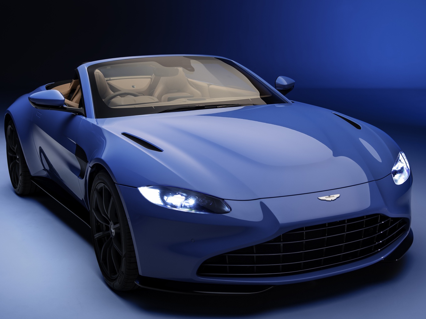 Кабриолет Aston Martin Vantage Roadster 2020 года на синем фоне