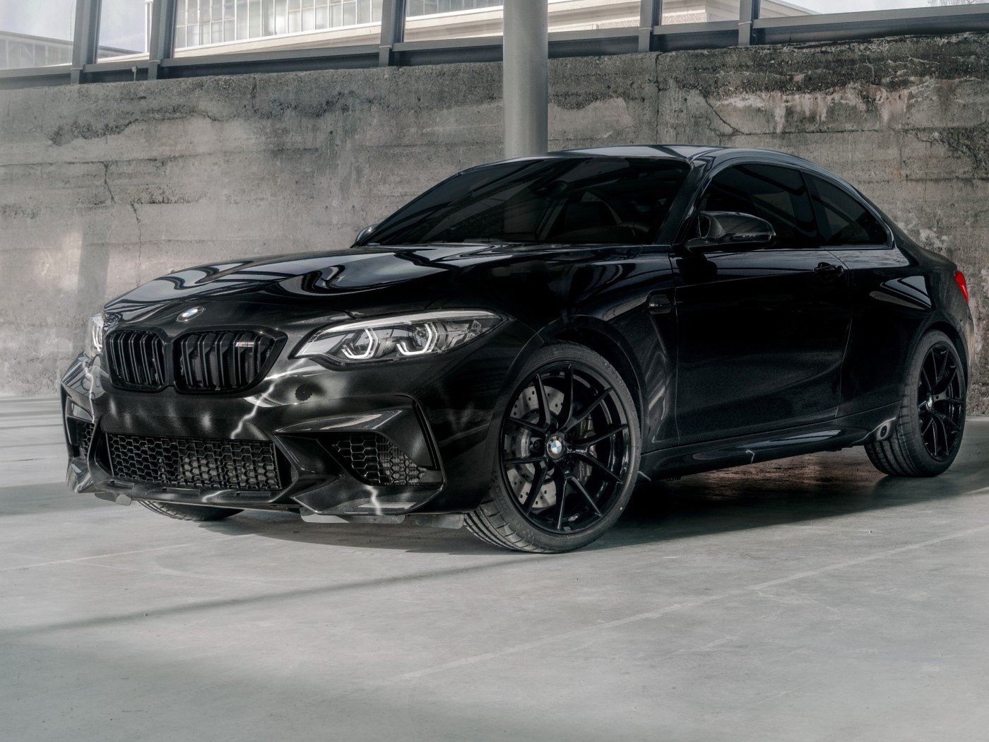 Черный автомобиль  BMW M2, 2020 года у бетонной стены