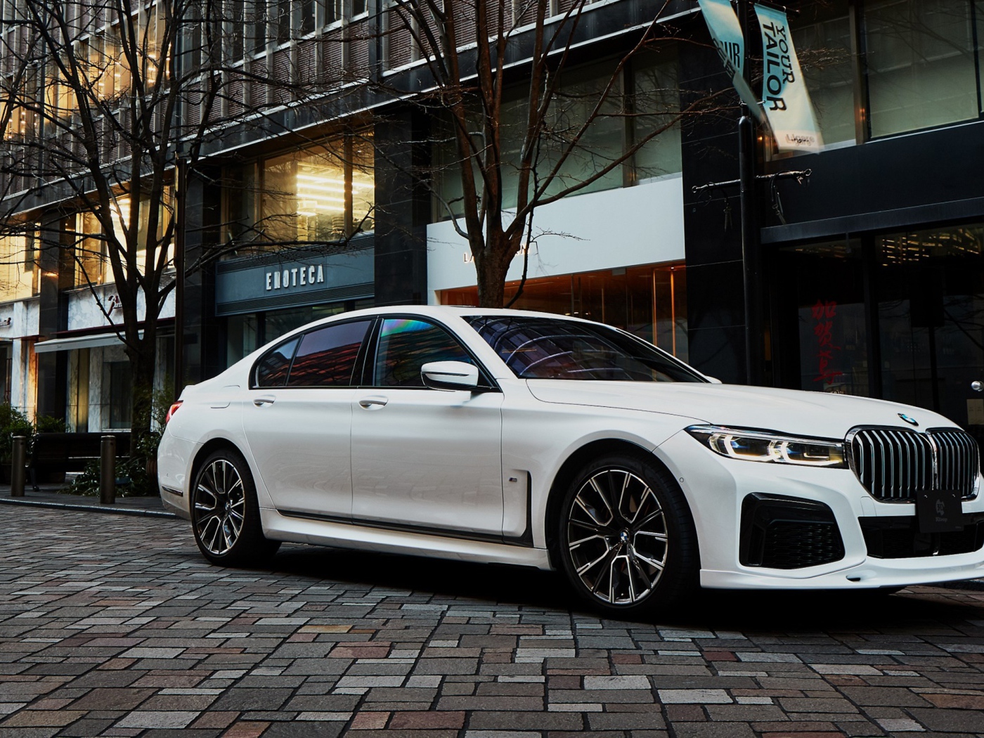 Белый автомобиль  BMW 740i M Sport 2020 года у кафе