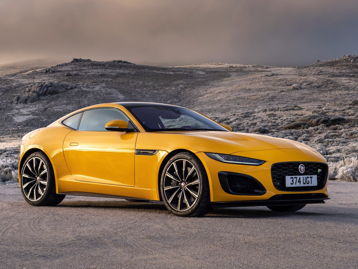 Желтый автомобиль Jaguar F-Type R Coupe 2020 года на фоне холмов