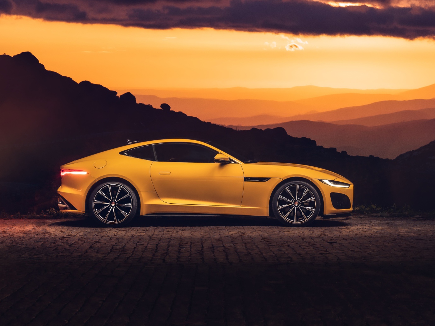 Желтый автомобиль jaguar f type 2020 года на закате 