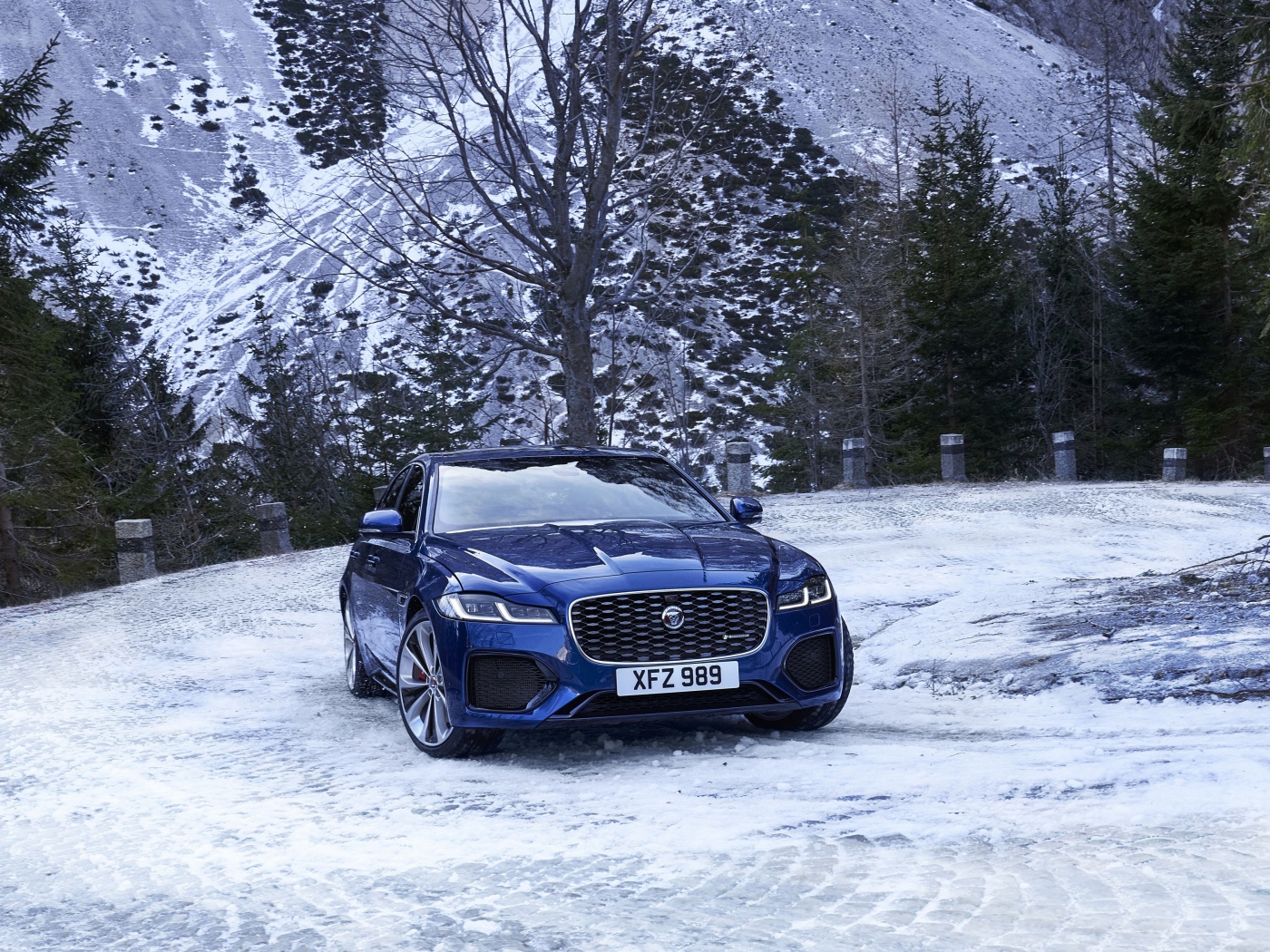 Синий автомобиль Jaguar XF зимой на фоне горы 