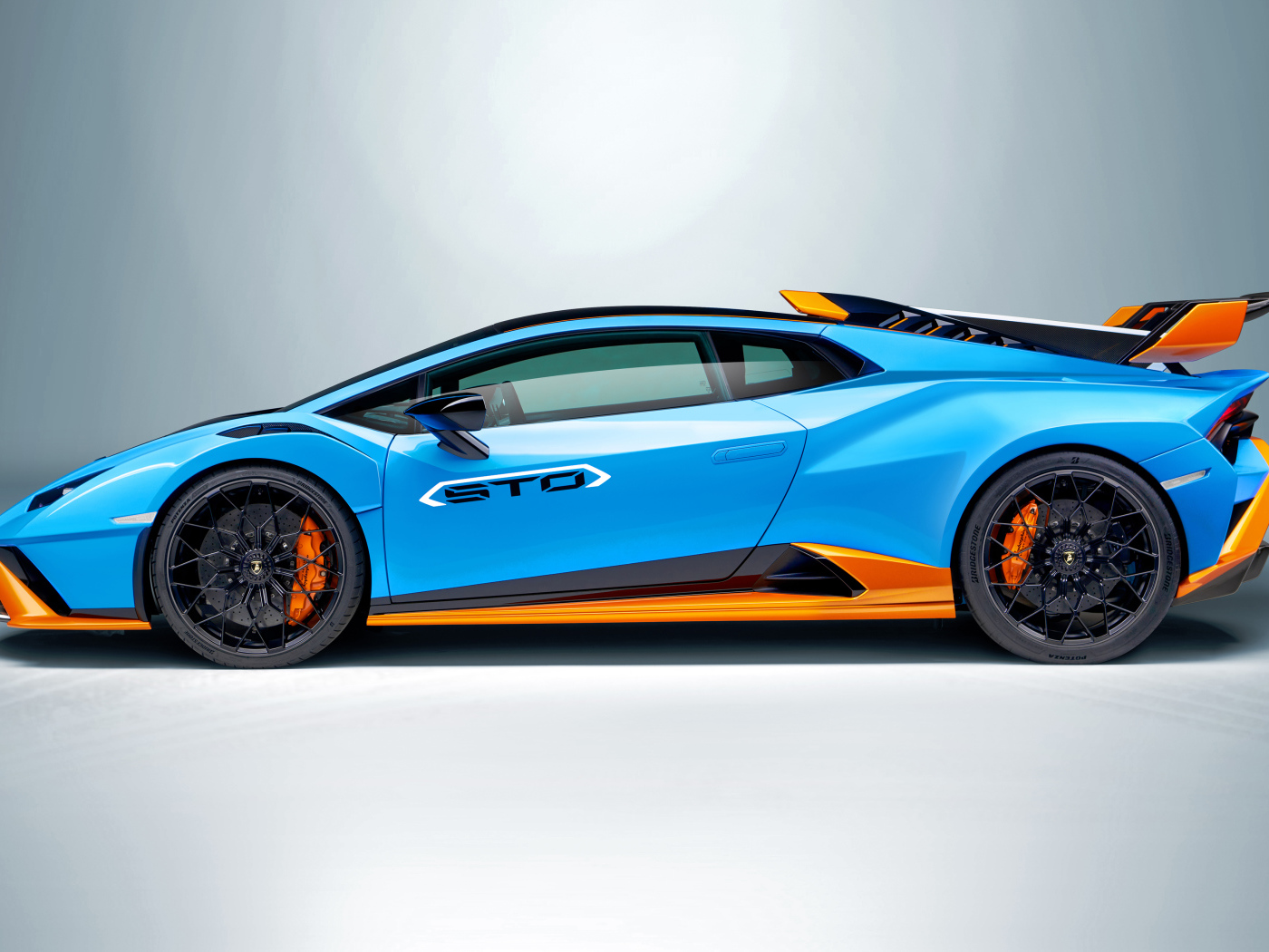 Голубой автомобиль Lamborghini Huracán STO 2021 года вид сбоку