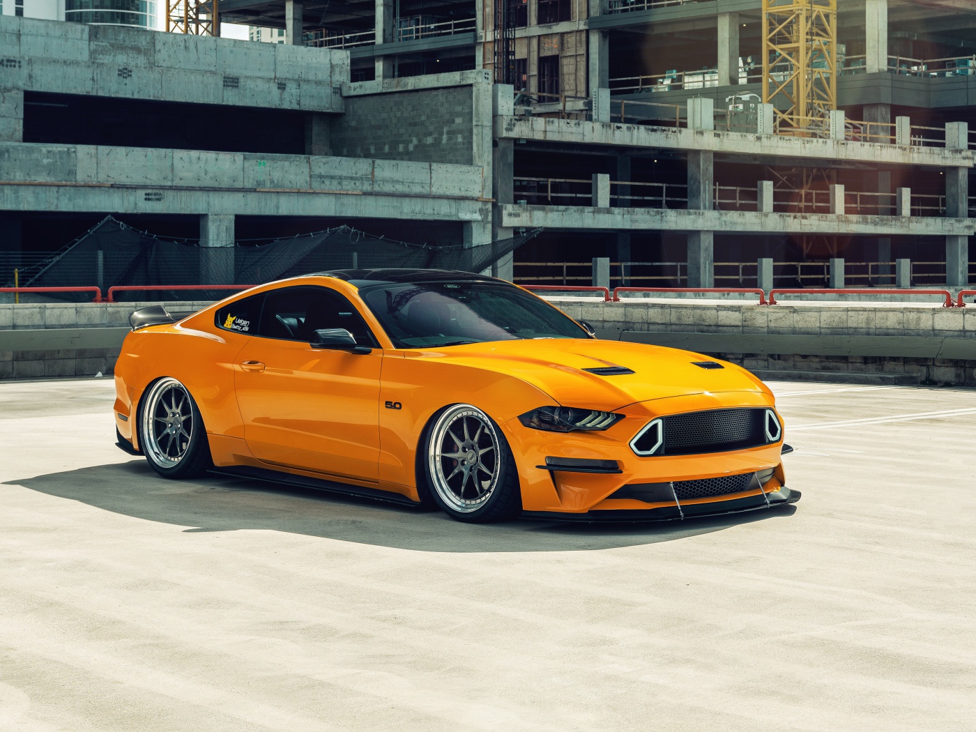 Оранжевый автомобиль Mustang у заброшенного здания 