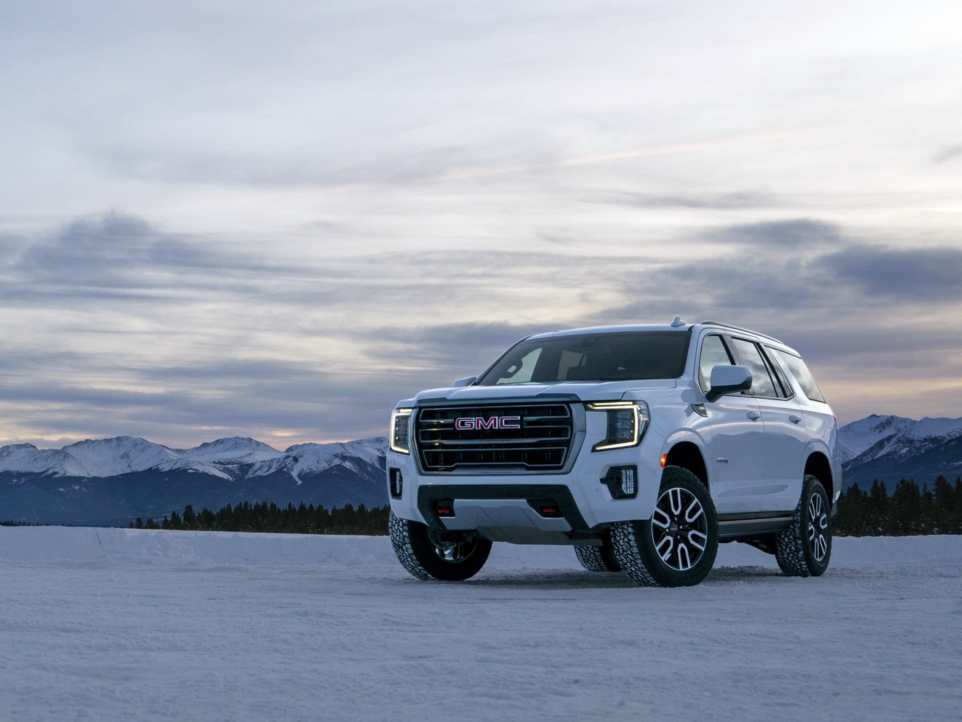 Белый внедорожник  GMC Yukon AT4, 2021 года на фоне заснеженных гор 