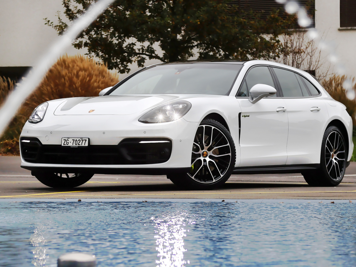 Белый автомобиль Porsche Panamera 4S E-Hybrid Sport Turismo 2020 года у бассейна