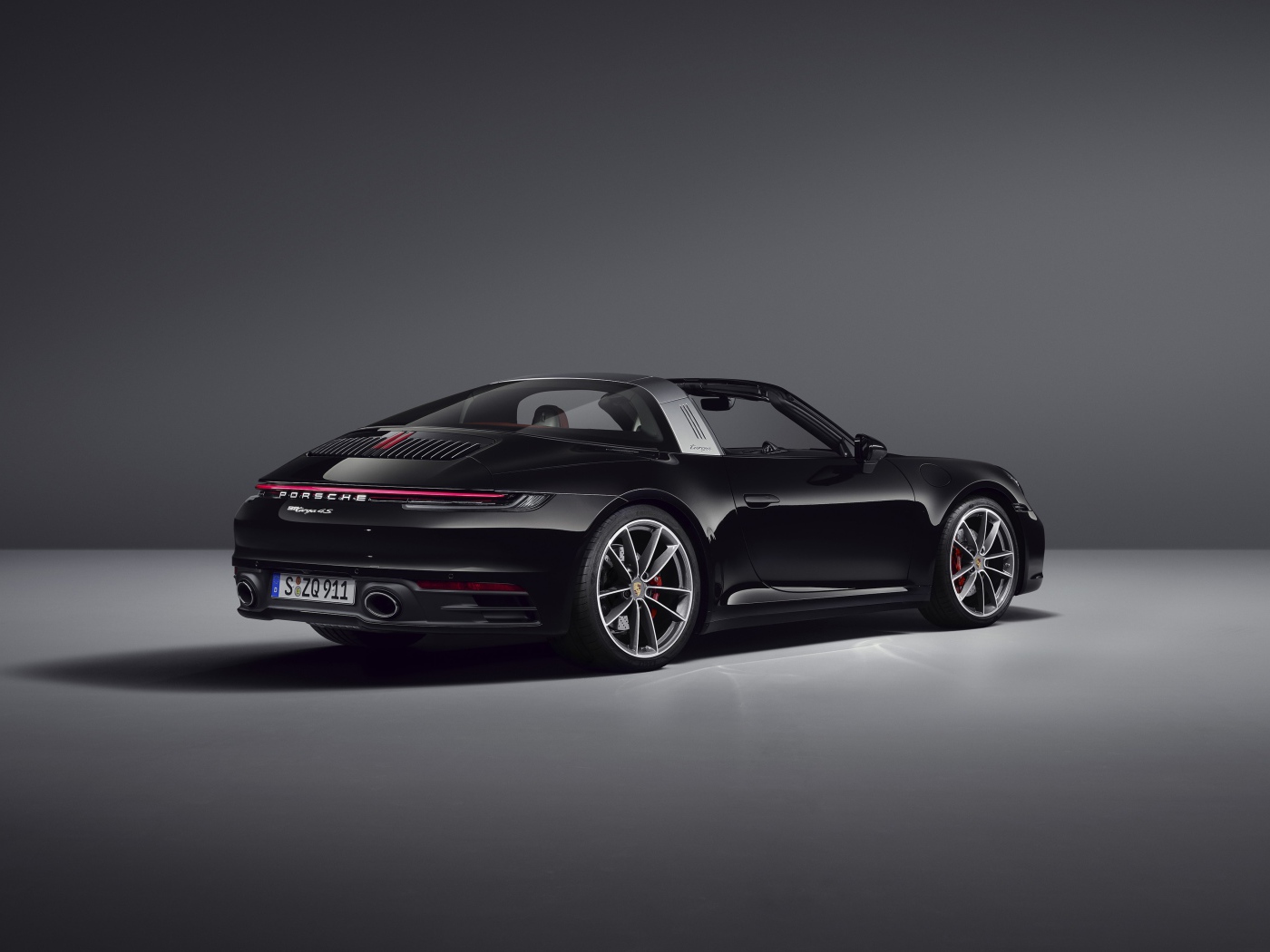 Черный автомобиль Porsche 911 Targa 4S 2020 года вид сзади на сером фоне