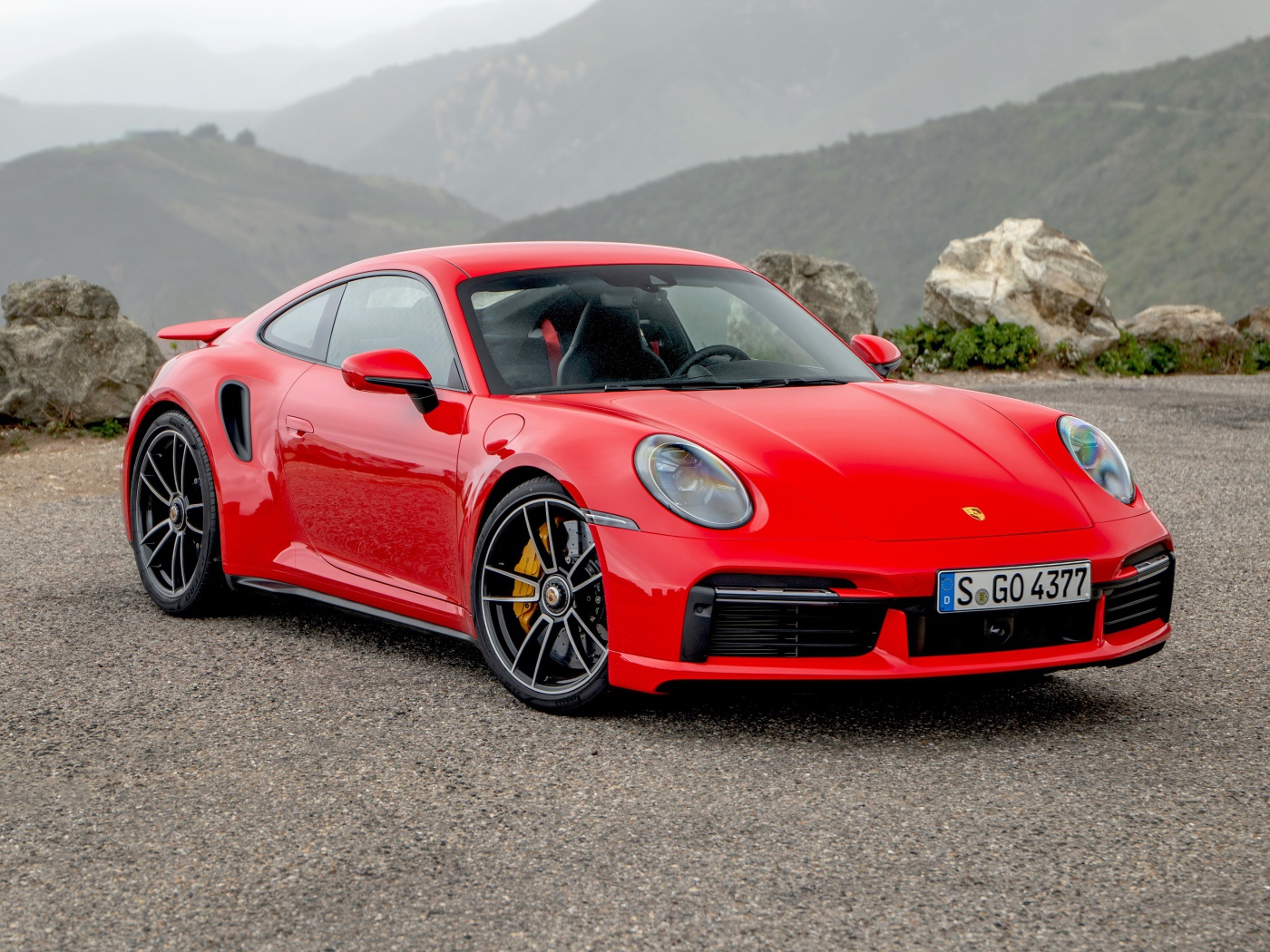 Красный автомобиль Porsche 911 Turbo S 2020 года на фоне гор 