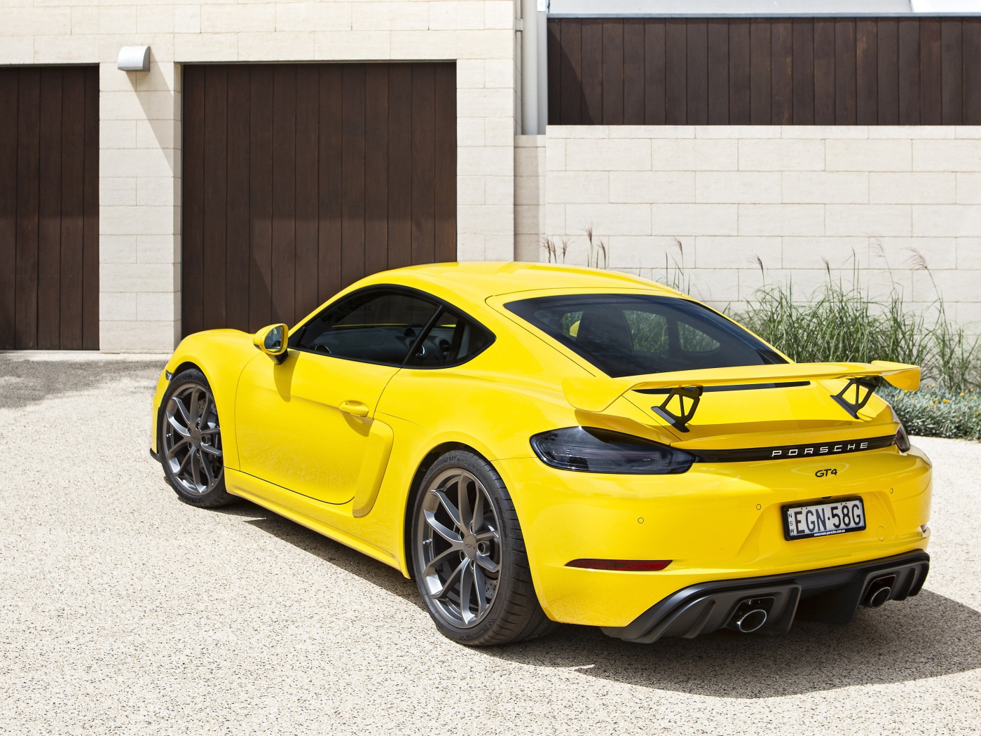 Желтый автомобиль Porsche 718 Cayman GT4, 2020 года у гаража 